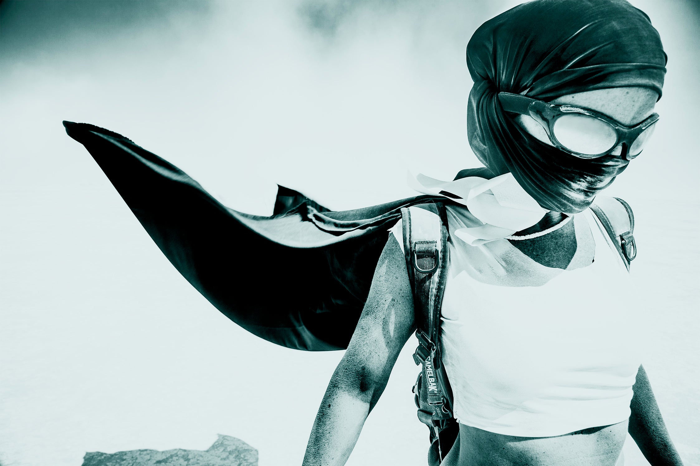 Person wearing a mask and cape in a superhero pose against a light background. burningman burning man 2013